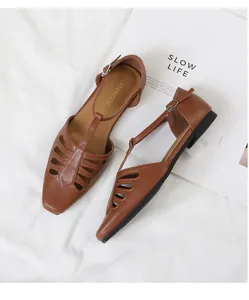 Close-up detail of vintage brown square-toe hollow-out leather T-strap flat sandals