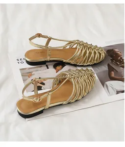 Detailed view of gold hand-woven closed-toe Roman sandals with elegant buckle straps.
