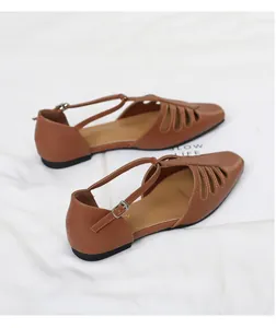 Close-up of vintage brown square-toe hollow-out flat sandals with T-strap buckle