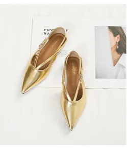 Detailansicht von goldenen flachen Schuhen mit spitzer Zehenpartie und Kreuzriemen