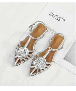 Elegant silver flat sandals featuring camellia flower accents and a T-strap design