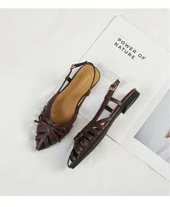 Detailed view of dark brown woven sandals with bow and hollow-out design