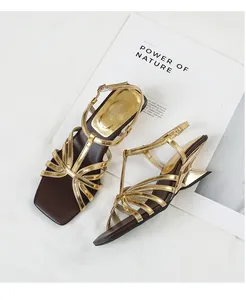 Vintage gold cross-strap sandals with square toe and sculptural heel on magazine prop