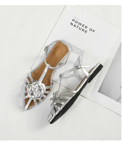 Detail view of silver camellia flat sandals featuring an elegant ankle strap closure