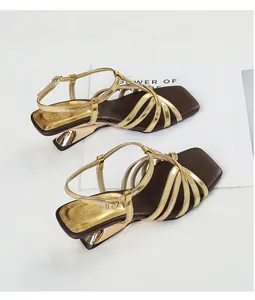 Elegant gold cross-strap sandals featuring square toe and sculptural metallic mid-heel detail