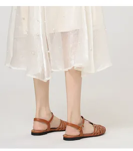 Detail view of brown T-strap hollow sandals paired with a pearl-embellished white skirt