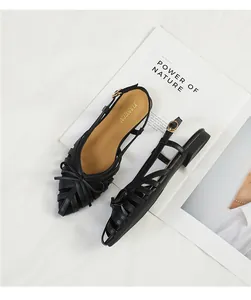 Detailed view of elegant black woven flat sandals with bow and slingback strap design
