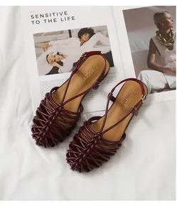 Detail shot of burgundy handmade woven closed-toe Roman sandals with a buckle strap.