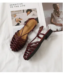 Close-up detail of burgundy hand-woven closed-toe Roman flat sandals with ankle strap