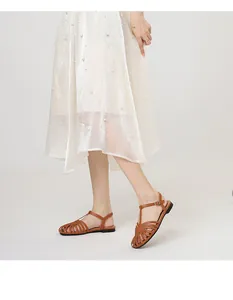 Retro brown hollow-out T-strap flat sandals worn by a model in a studio setting