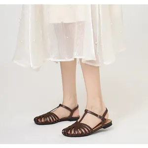 Detailed view of vintage hollow-out closed-toe T-strap flat brown sandals for women.
