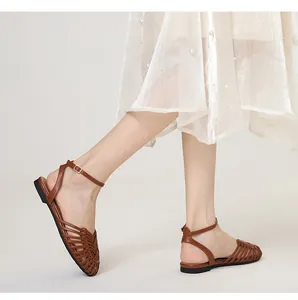 Detailed side view of hand-woven brown Roman flat sandals with elegant ankle strap buckle