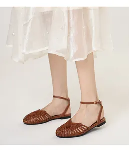 Close-up view of retro brown woven leather sandals with buckle ankle strap on a model