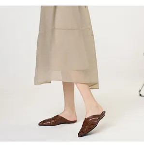 Close-up detail of stylish brown woven leather pointed-toe mule slippers for women