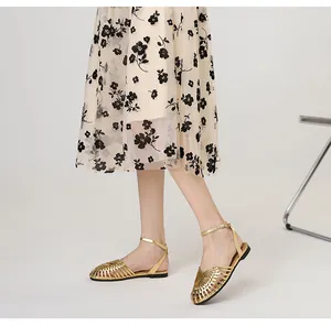 Close-up of retro gold hand-woven flat Roman sandals with an elegant ankle strap detail