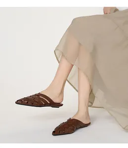 Close-up detail of brown woven leather pointed-toe mule sandals worn on a model