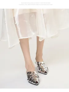Detailed view of silver woven pointed-toe mules paired with a sheer pearled skirt.