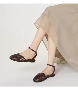 Close-up of brown hand-woven Roman fisherman sandals worn with an elegant skirt