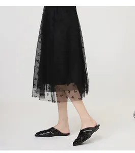 Close-up detail of stylish black woven pointed-toe mules worn with a lace mesh skirt