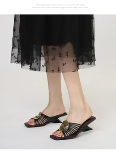 Side view detail of French-style black heeled mules with golden metallic ornament