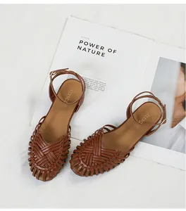 Detailed view of brown woven Roman sandals with ankle strap and closed toe design