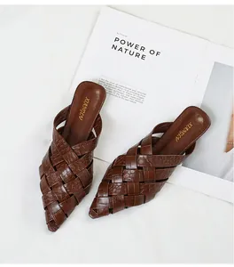 Detailed view of brown woven pointed-toe mules featuring a textured crocodile pattern design
