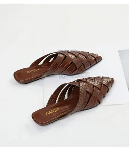 Detailed view of brown woven pointed-toe mules with crocodile texture finish