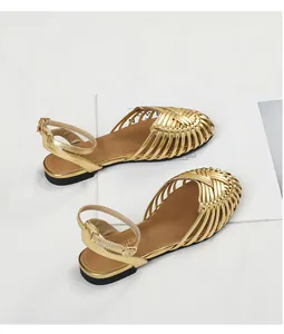 Detail view of vintage gold hand-woven flat sandals with adjustable ankle strap closure.