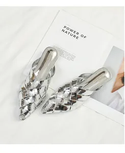 Close-up detail of silver woven texture on fashion pointed-toe mules on white bedding