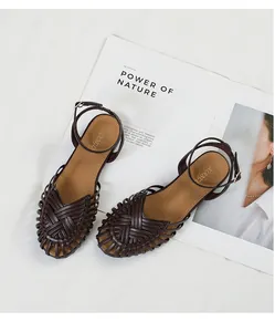 Detailed view of brown hand-woven retro Roman style flat sandals on an open magazine
