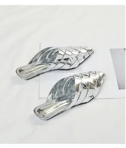 Macro detail of women's silver woven pointed-toe mule slippers with metallic finish