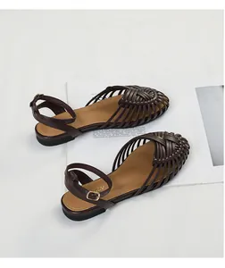 Detailed macro view of dark brown hand-woven Roman closed-toe flat sandals for women