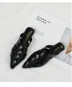 Detailed view of black woven pointed-toe mule sandals featuring a glossy finish.