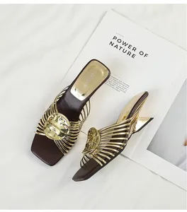 Close-up of gold metallic sandals with radiating straps and unique geometric heels.
