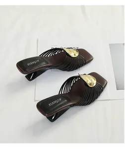 Detailed view of French-style brown sandals with gold metal leaf and black radiating straps.