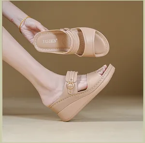 Detail of elegant beige wedge sandals featuring contrast stitching and gold buckle