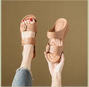 Detailed view showing the intricate floral accents and laser-cut patterns on camel wedge sandals