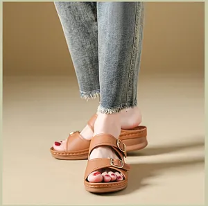 Close-up of stylish brown platform wedge sandals with double gold buckle straps on feet