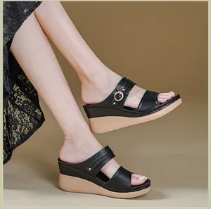 Close-up of black wedge sandals with elegant contrast stitching and gold buckle