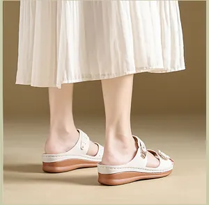 Detail view of white flower wedge sandals with vintage decorative stitching.