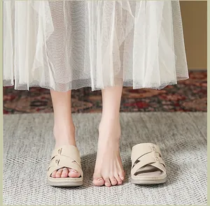 Dettaglio di sandali con zeppa beige con cinturini incrociati e fibbie metalliche