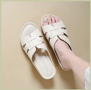 Close-up of cream wedge sandals with stitched H-strap design and soft footbed.