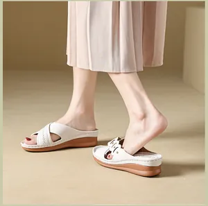 Elegant detail view of women's cream wedge sandals with laser-cut scalloped edges