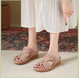 Close-up of women's beige wedge sandals with cutout detail worn with a white dress