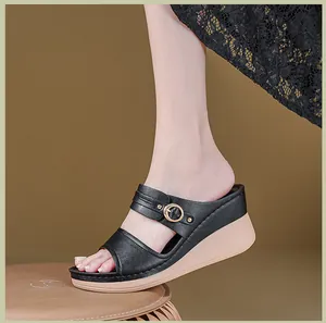Detailed close-up of women's black wedge sandals with decorative stitching and buckle.