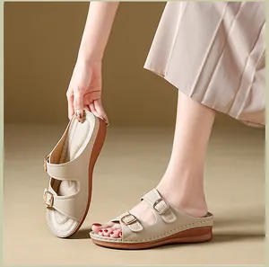 Close-up detail of women's beige wedge sandals with buckle straps worn by a model.