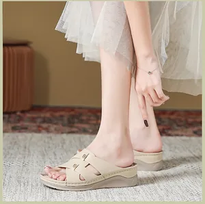 Dettaglio di sandali con zeppa beige con cinturini incrociati e decorazioni oro