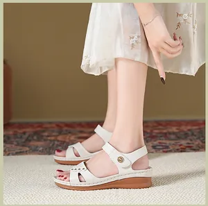 Vue latérale de sandales compensées blanches avec boucle en métal aux pieds d'un modèle
