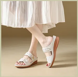 Side view of elegant white wedge sandals featuring delicate flower and perforated straps