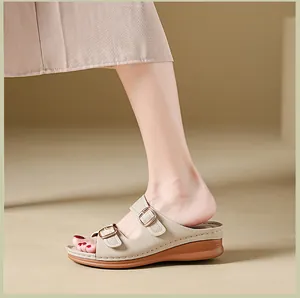 Side view of a beige women's wedge sandal featuring adjustable gold buckles